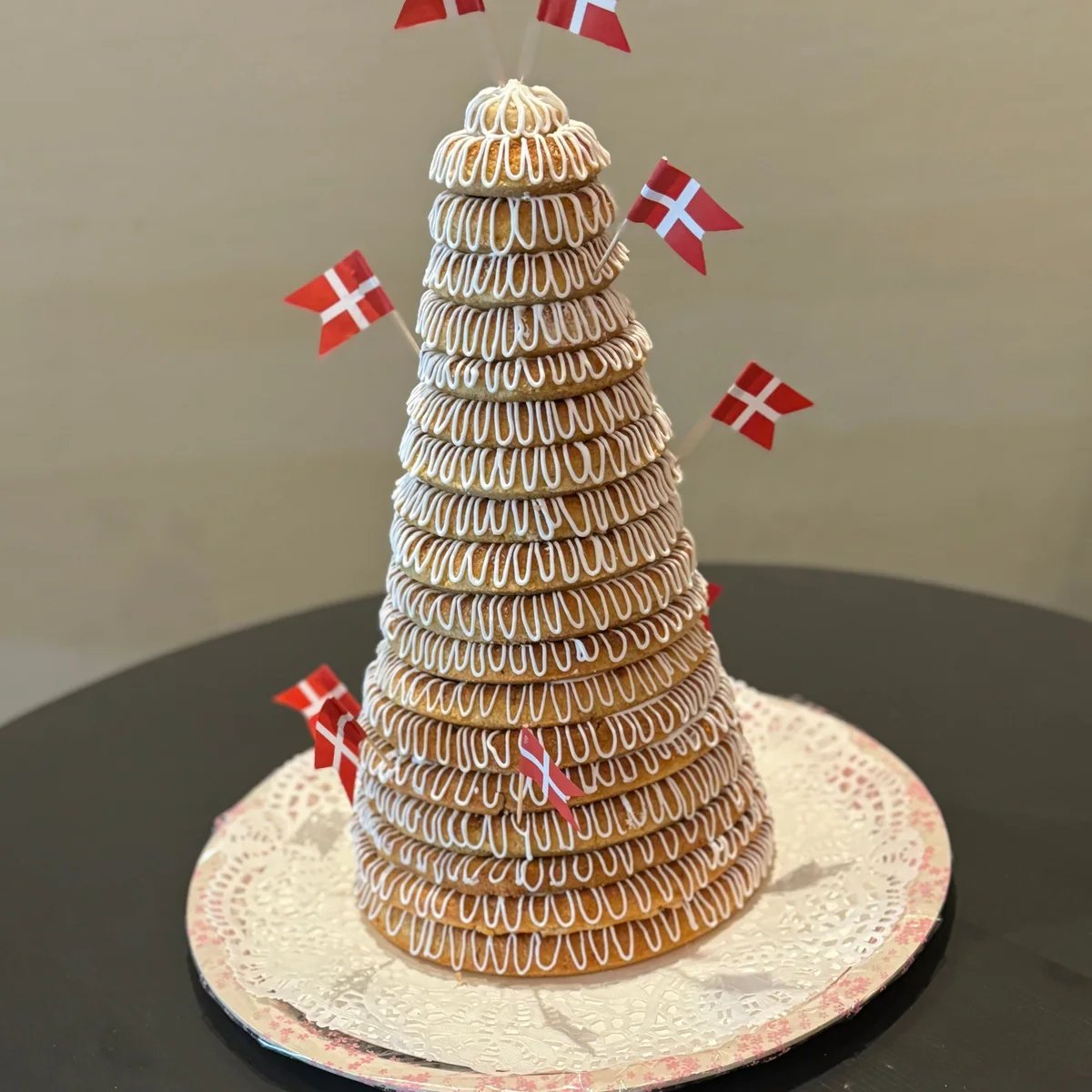 Ett torn av kransekageringar med kristyr och danska flaggor i, på silverfat