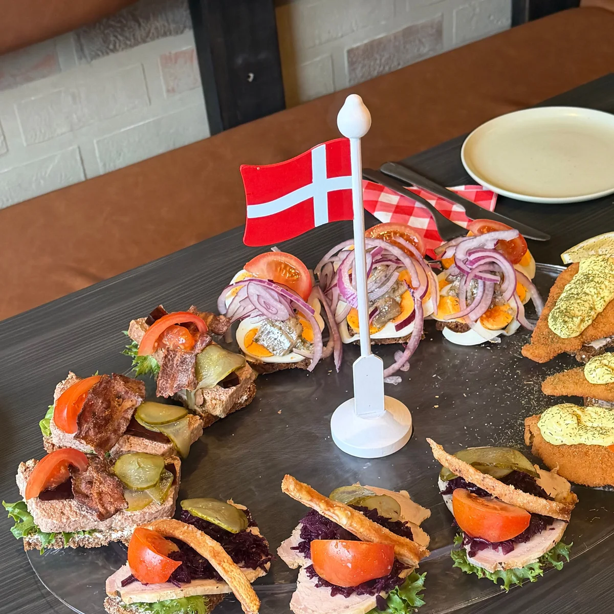 Uppdukat fat med danska smørrebrød och en dansk flagga på bordet